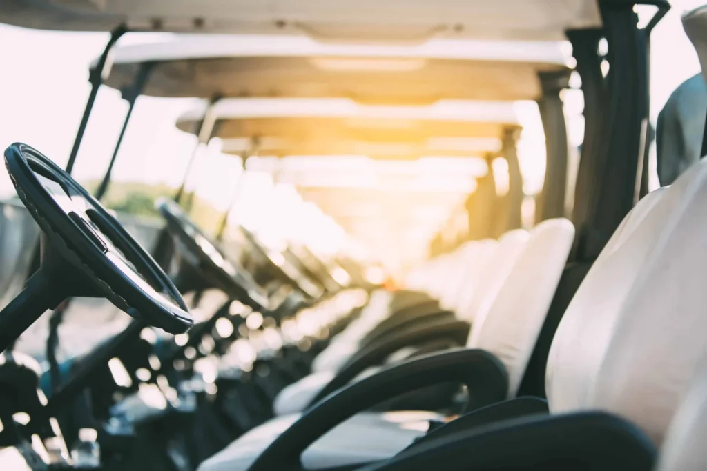 Row of parked golf carts showing steering wheels and seats