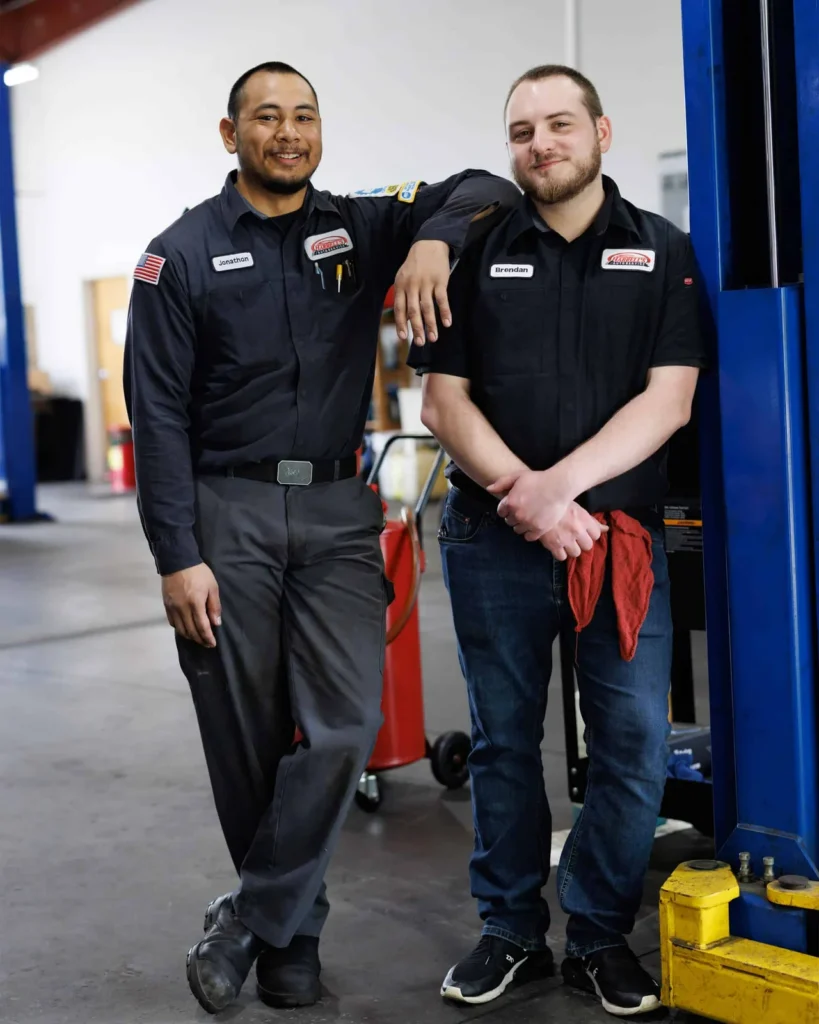 Two Harrell’s automotive technicians standing beside a vehicle lift